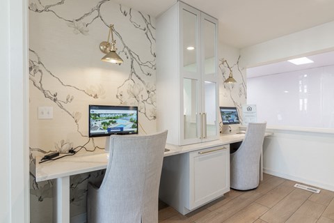 A white desk with a computer and chair in front of a cabinet with a wall hanging. at Sundance Apartments, Indianapolis