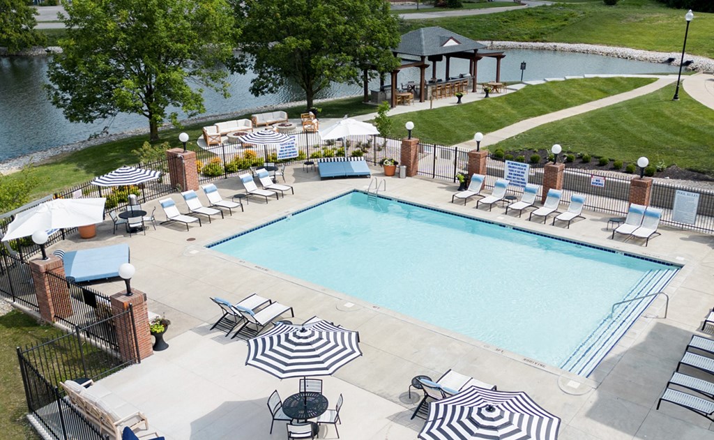 A large outdoor swimming pool surrounded by lounge chairs and umbrellas. A large outdoor swimming pool surrounded by lounge chairs and umbrellas. at Sundance Apartments, Indianapolis, IN, 46237