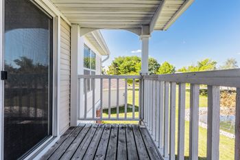 A porch with a white railing and a wooden floor