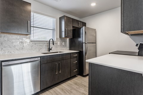 A modern kitchen with dark wood cabinets and stainless steel appliances. at Sundance Apartments, Indiana, 46237