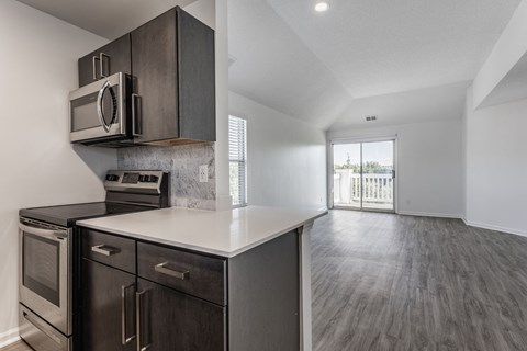 A modern kitchen with dark wood cabinets and stainless steel appliances. at Sundance Apartments, Indianapolis, IN