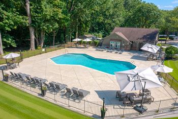 A large outdoor swimming pool surrounded by lawn chairs and umbrellas.
