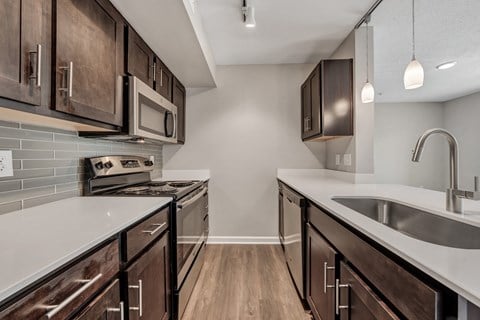 A kitchen with dark wood cabinets and a white countertop.