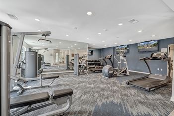 A spacious gym with a variety of equipment including treadmills, weight machines, and a rowing machine. at Sunscape Apartments, Roanoke, Virginia