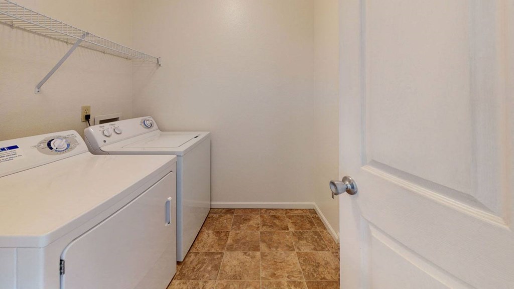 a washer and dryer in a laundry room with a white door at Tall Oaks Apartment Homes, Kalamazoo, 49009