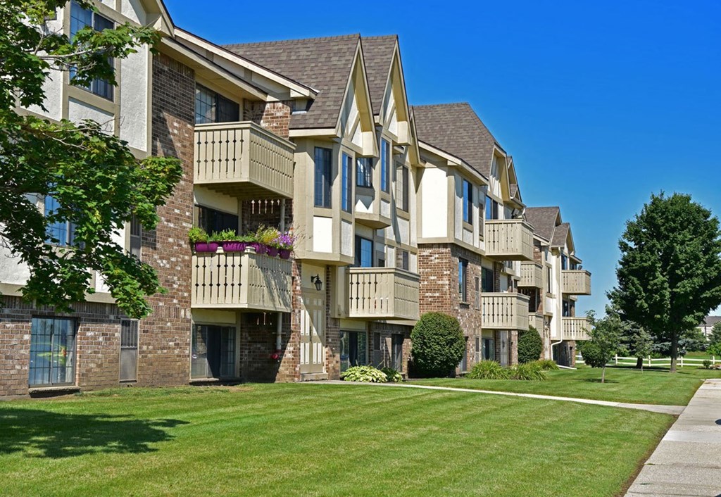 an apartment building on a sunny day with a grassy area in front of it at Tanglewood Apartments, Oak Creek, Wisconsin