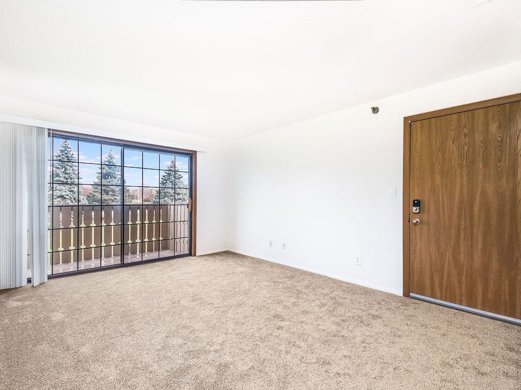 an empty living room with a door to a balcony at Tanglewood Apartments, Wisconsin, 53154