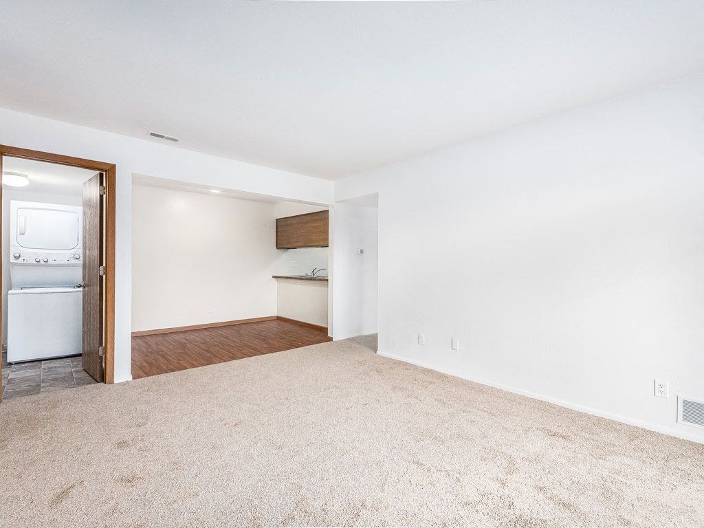 an empty living room with an open door to a laundry room at Tanglewood Apartments, Oak Creek