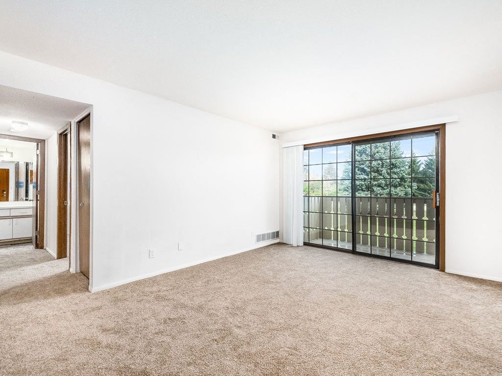 an empty living room with a large window and carpeting at Tanglewood Apartments, Wisconsin