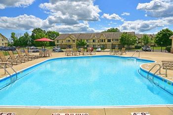 a swimming pool with chaise lounge chairs and a building in the background at Tanglewood Apartments, Wisconsin, 53154
