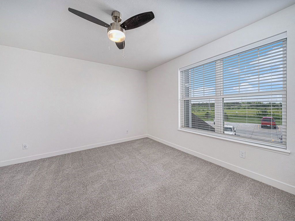 bedroom with a large window and a ceiling fan at Trade Winds Apartment Homes, Elkhorn, Nebraska