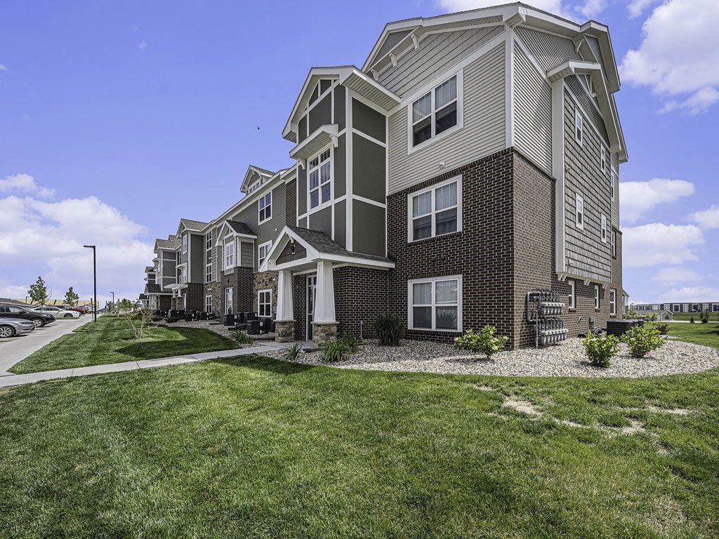 apartment building with grass and sidewalks at Trade Winds Apartment Homes in Elkhorn, NE 68022