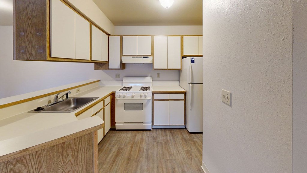 kitchen with white appliances and breakfast bar  at Trappers Cove Apartments, Lansing, MI