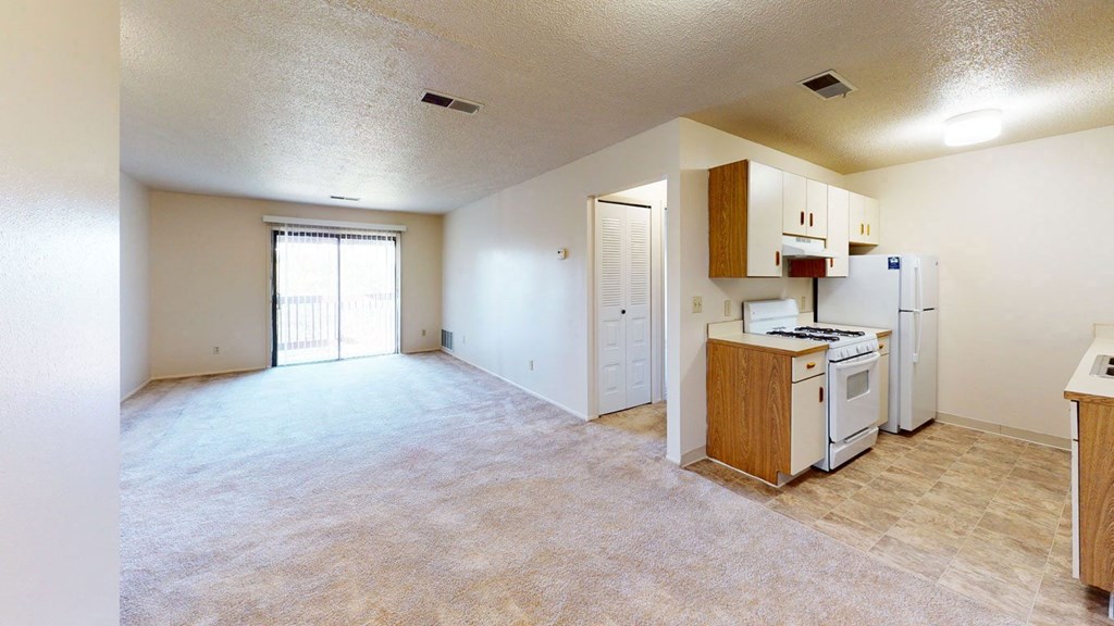 galley style kitchen and living room with a slider to a balcony at Trappers Cove Apartments, Michigan, 48910