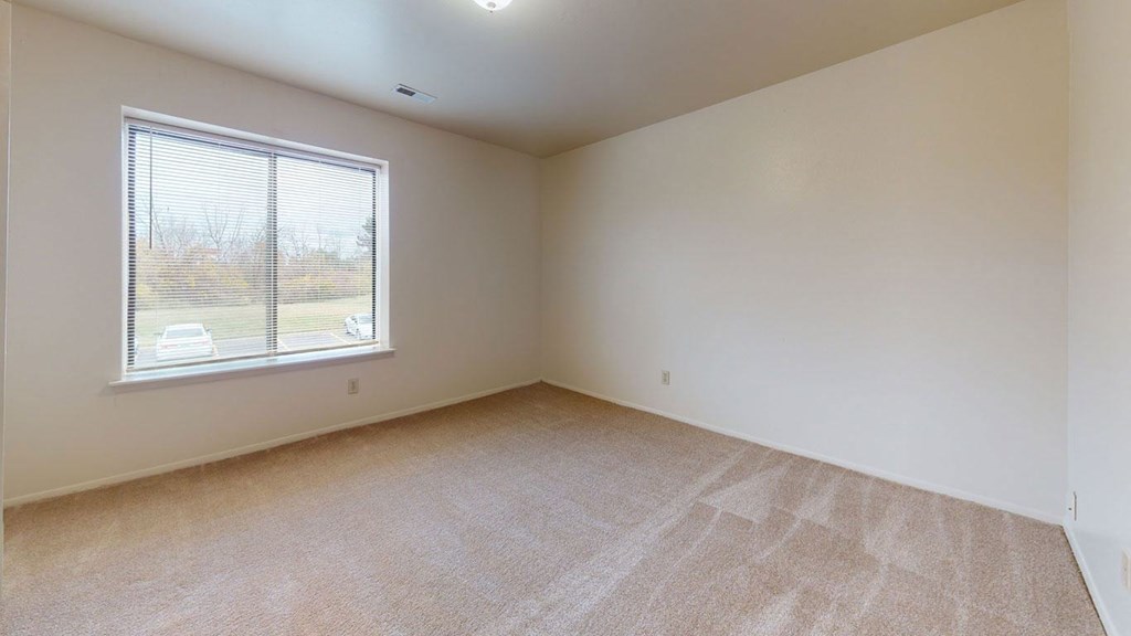 bedroom with a window and carpet at Trappers Cove Apartments, Lansing