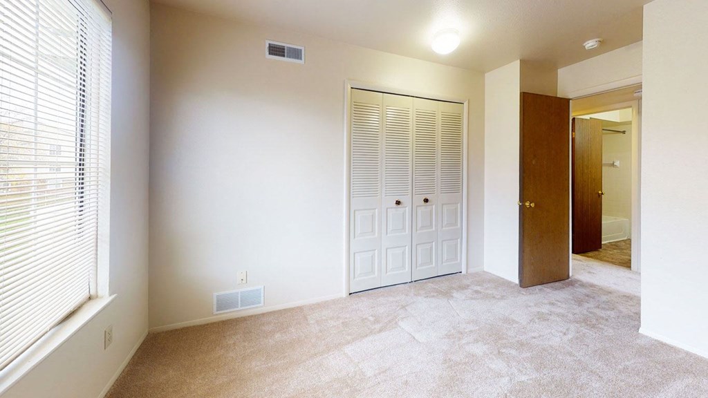 bedroom with a closet and a large window  at Trappers Cove Apartments, Lansing