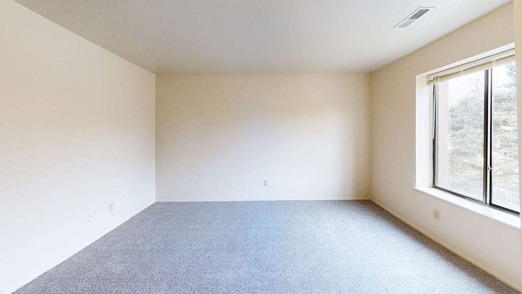 spacious bedroom with a large window and carpet  at Trappers Cove Apartments, Lansing, Michigan