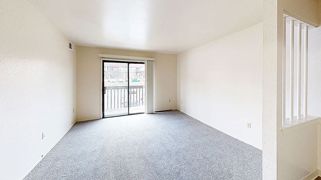 an empty living room with a door to a balcony  at Trappers Cove Apartments, Lansing, MI, 48910