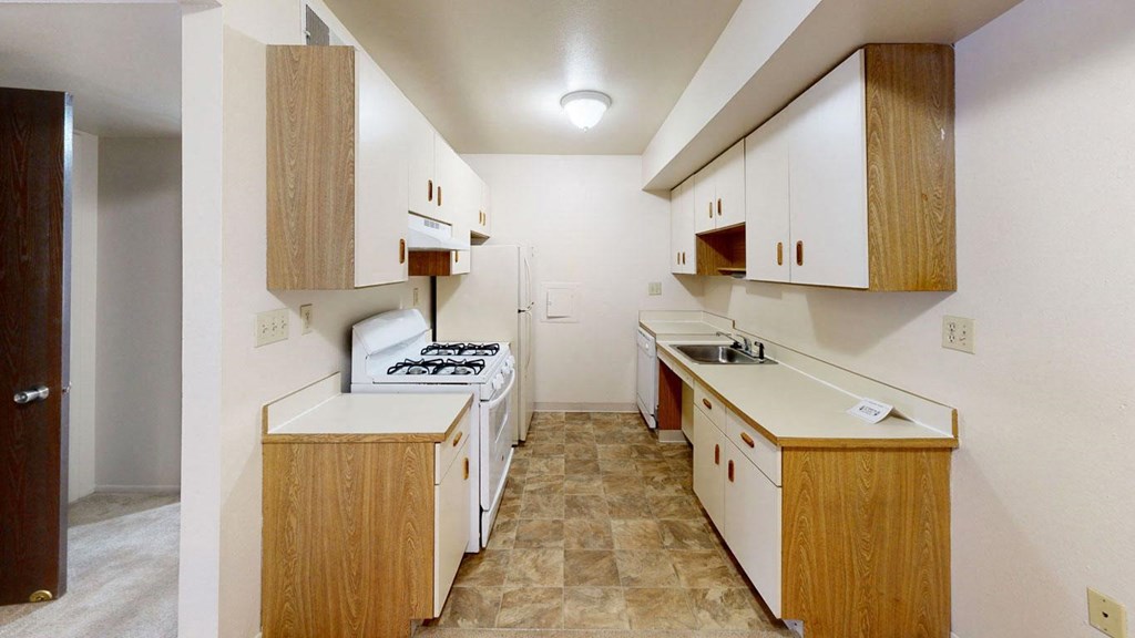 an equipped kitchen with white appliances  at Trappers Cove Apartments, Lansing, Michigan