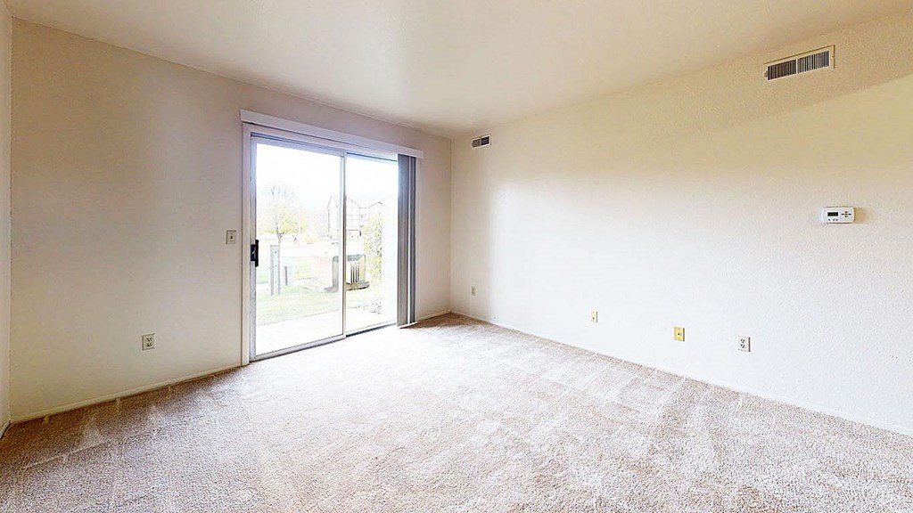 living room with a sliding glass door to a private patio at Trappers Cove Apartments, Michigan