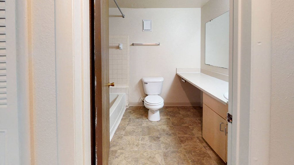a bathroom with a toilet and a tub and a sink at Trappers Cove Apartments, Lansing, MI