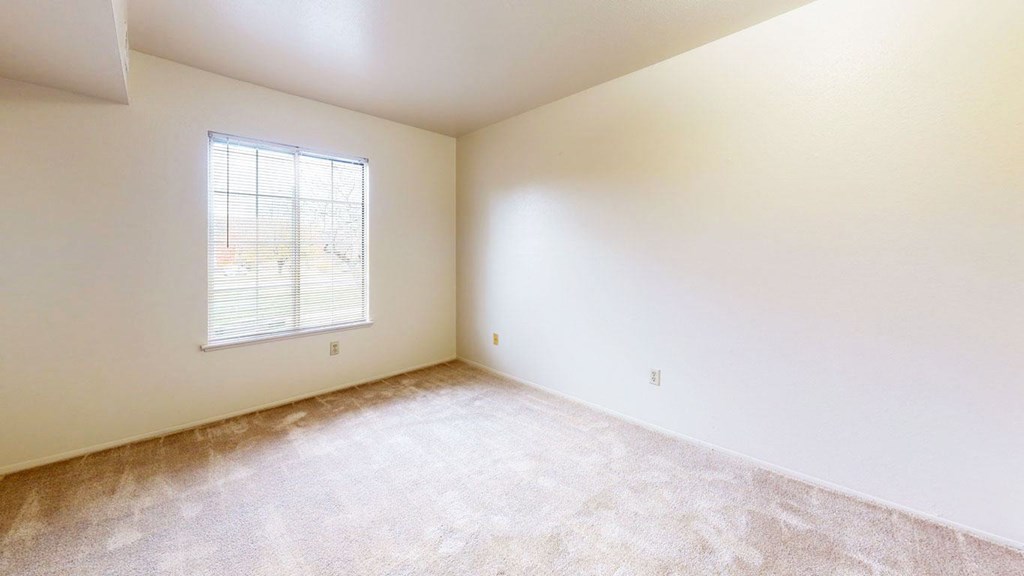 a large bedroom with carpet and a window at Trappers Cove Apartments, Lansing, MI, 48910