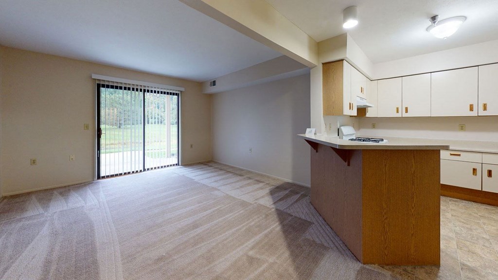 an empty living room and kitchen with a sliding glass door at Trillium Pointe Apartment Homes, Jackson, MI