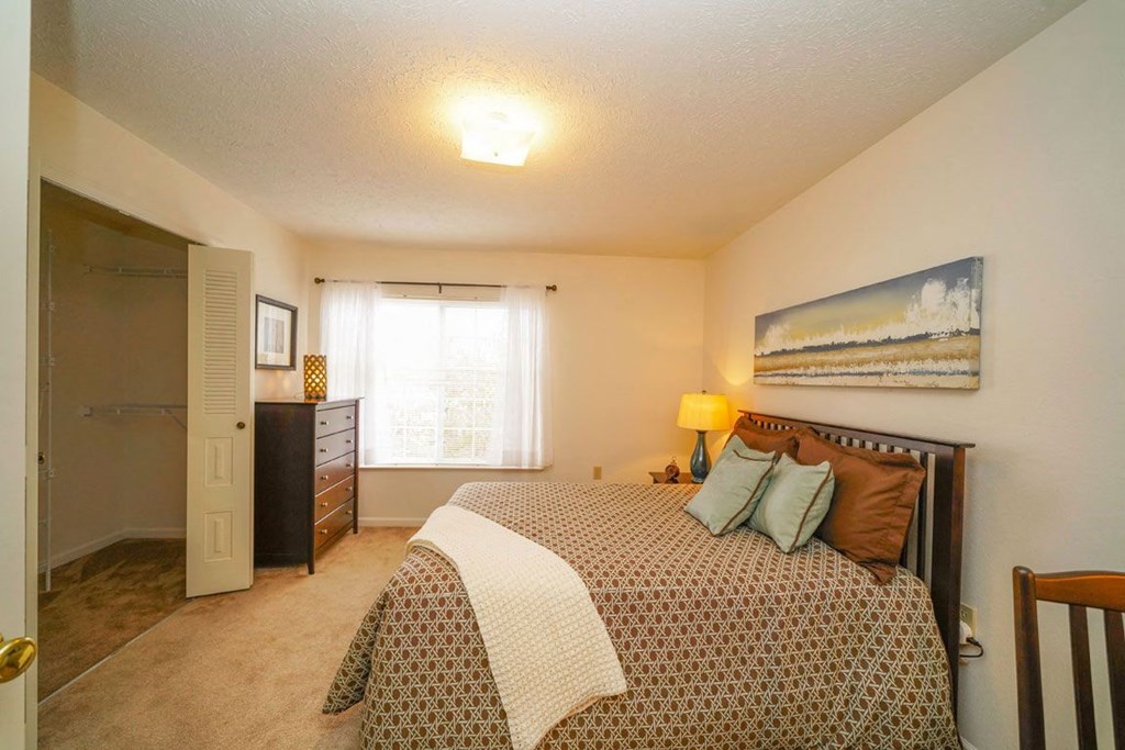 a bedroom with a walk-in closet and large window a bedroom with a walk-in closet and large window at Trillium Pointe Apartment Homes, Michigan