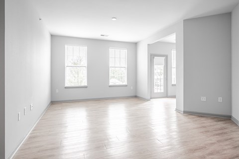 A large empty room with wooden floors and windows.