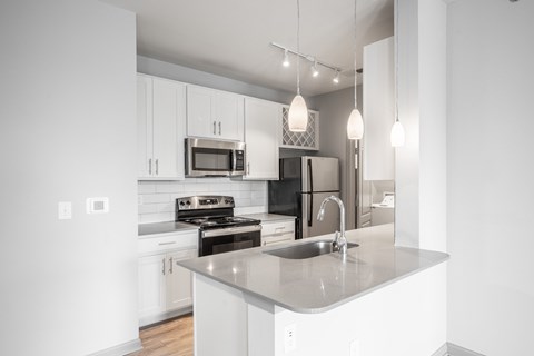 A modern kitchen with a stainless steel sink and white cabinets.