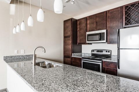 A kitchen with a granite countertop and stainless steel appliances.