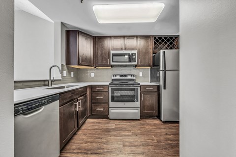 an empty kitchen with stainless steel appliances and wooden cabinets at Trophy Club at Bellgrade, Midlothian, VA, 23113
