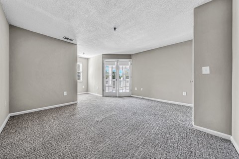 an empty living room with gray walls and a door to a balcony at Trophy Club at Bellgrade, Midlothian, VA, 23113