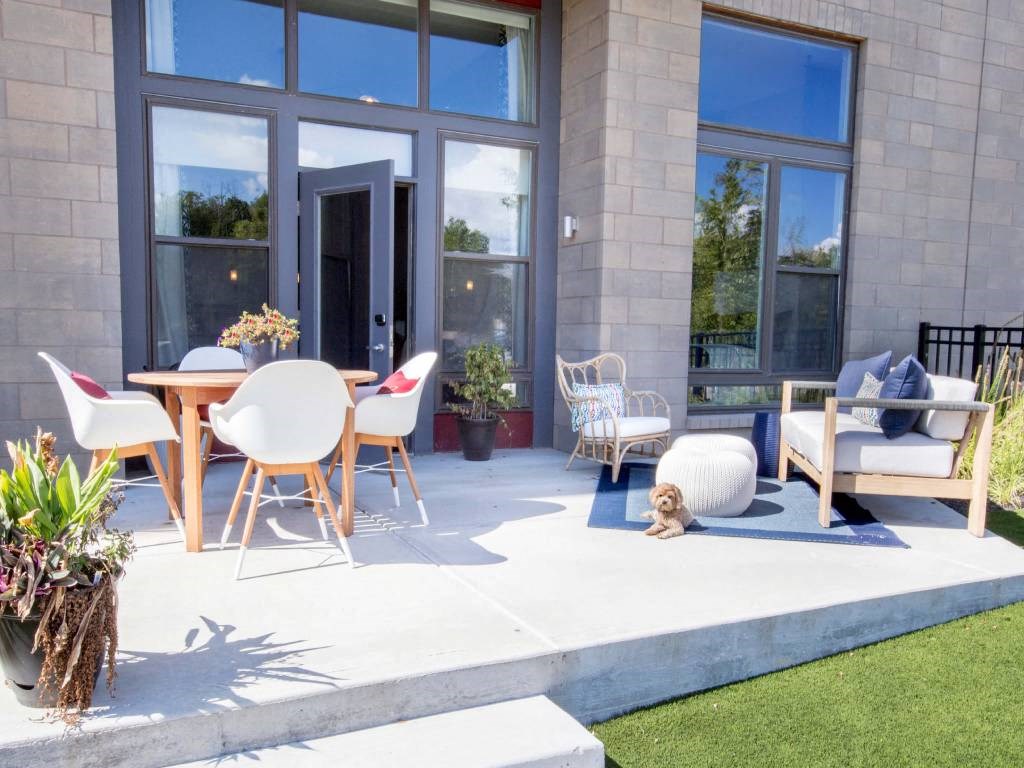 a patio with a table and chairs and a dog laying on the ground  at Avant & Avant II, Carmel, IN, 46032