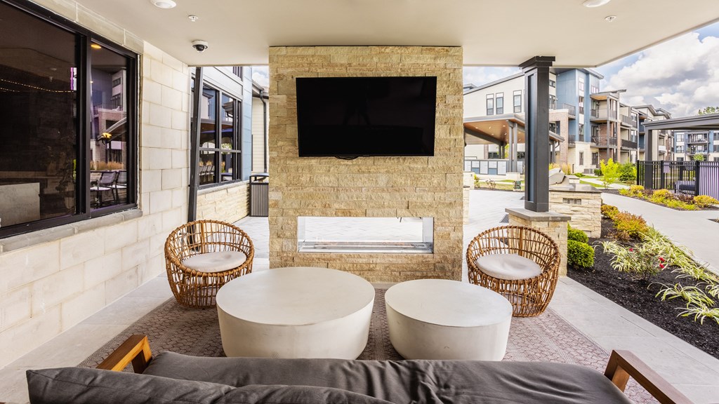 Modern outdoor seating area with a flat screen TV mounted on a stone wall at Upper Vue Flats, Dublin, Ohio