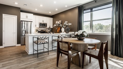 A kitchen with a table and chairs in front of a window.