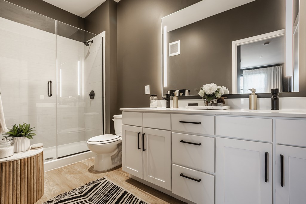 A modern bathroom with a glass shower, white cabinetry, and a large mirror at Upper Vue Flats, Dublin