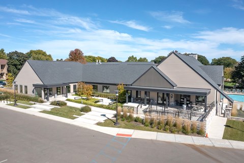 A large building with a grey roof and a pool in front.