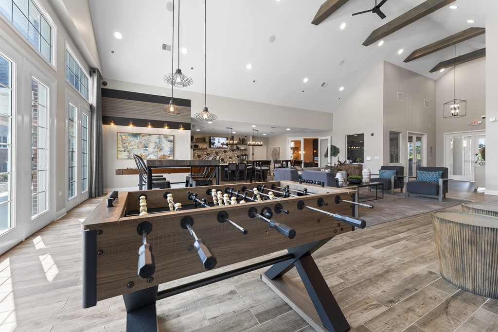 A foosball table is in the middle of a room with a bar and a fireplace.