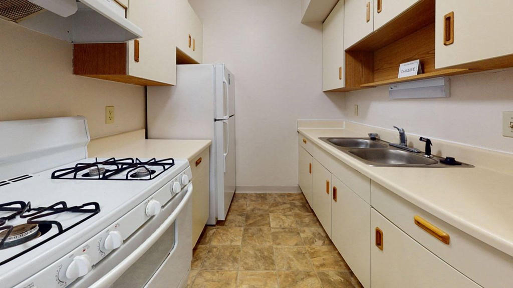 a kitchen with a stove and a sink and a refrigerator at Waverly Park Apartments in Lansing, MI 48911