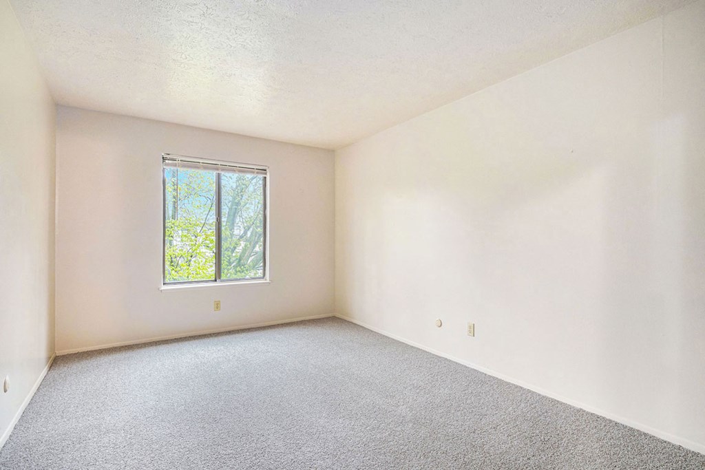 Large bedroom with a window and carpet at Wingate Apartments, Kentwood, 49512