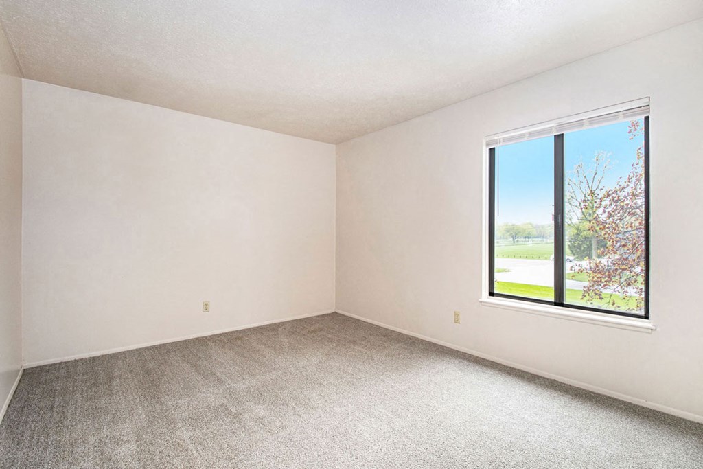 bedroom with a large window and carpeting at Wingate Apartments, Kentwood, 49512