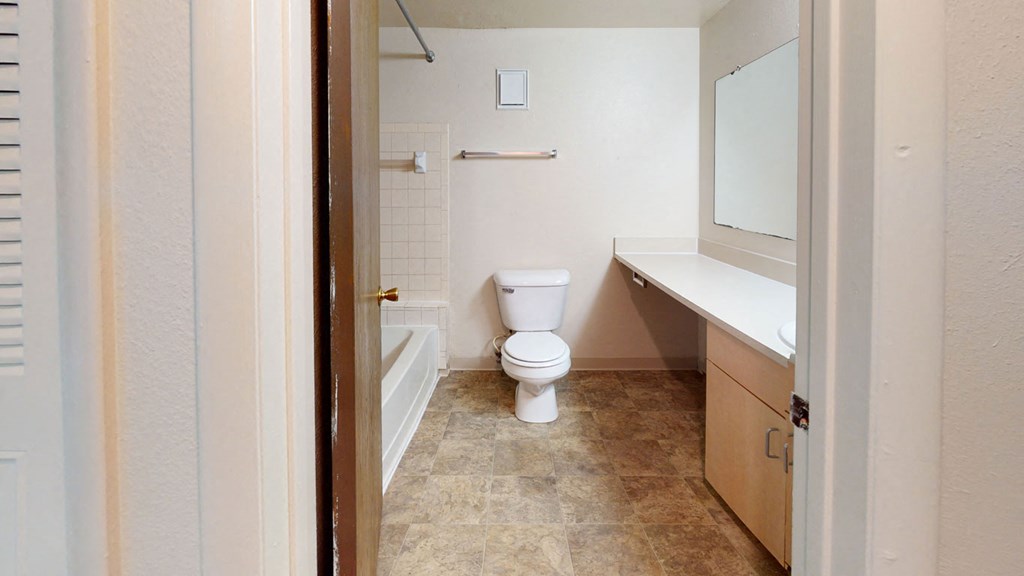 a bathroom with a toilet and a tub and a sink  at Wood Creek Apartments, Kenosha, 53144