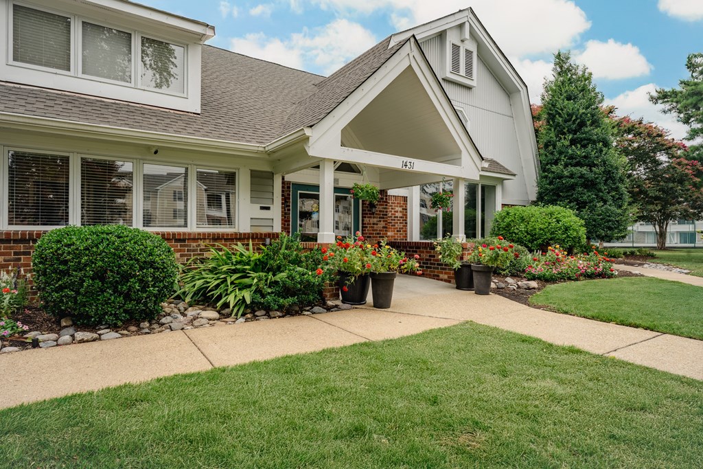 A house with a white front porch and a green lawn.
