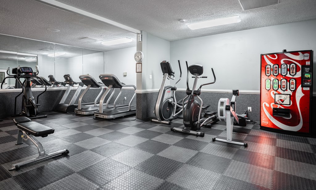 A gym with a variety of exercise equipment including treadmills, stationary bikes, and weight machines.