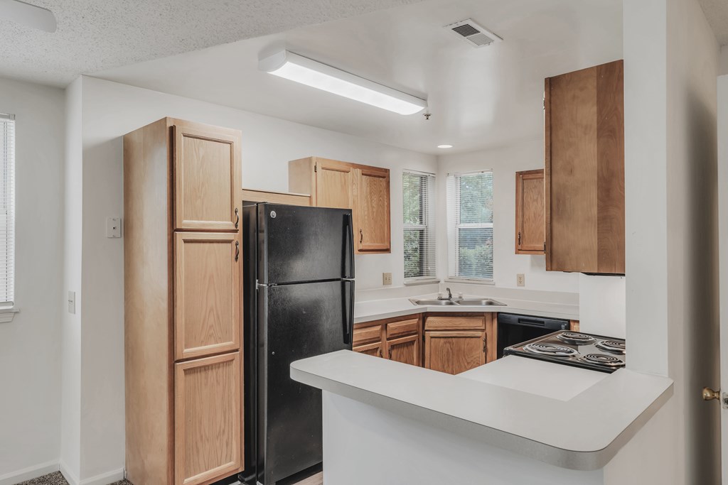 A kitchen with a black refrigerator and wooden cabinets at WaterFront Apartments, Virginia Beach, 23453