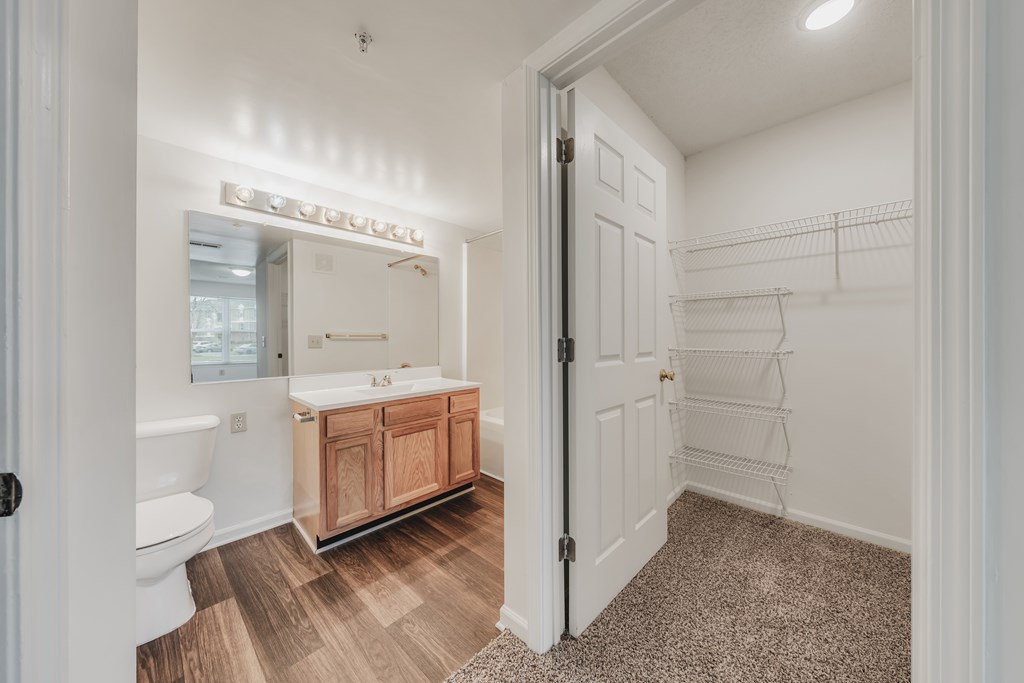 A bathroom with a white tub and sink, a wooden cabinet, and a white door at WaterFront Apartments, Virginia Beach, 23453