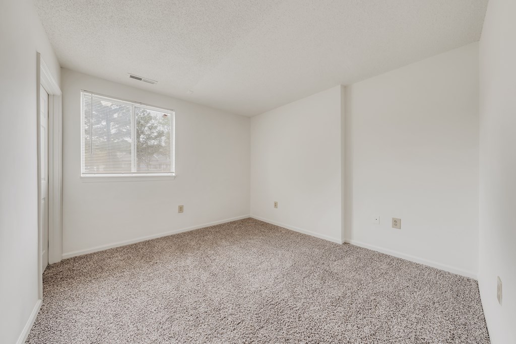 A room with a carpeted floor and a window with blinds at WaterFront Apartments, Virginia Beach, 23453