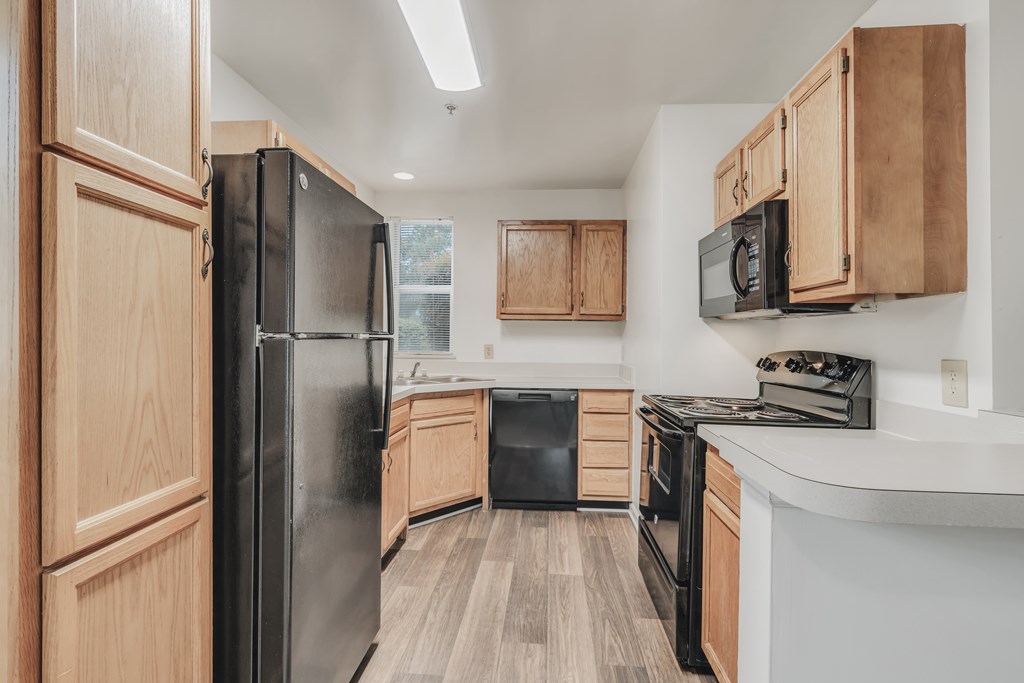 A kitchen with wooden cabinets and black appliances at WaterFront Apartments, Virginia Beach, 23453