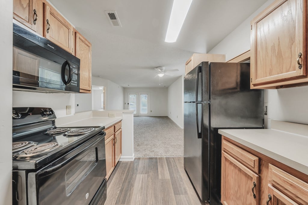 A kitchen with black appliances and wooden cabinets at WaterFront Apartments, Virginia Beach, 23453